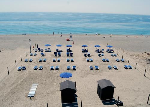 a beach with a bunch of chairs and umbrellas at Villa Nettuno Residence in Giardini Naxos