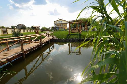a small pond with a wooden bridge and a playground at Casa Vlad in Murighiol