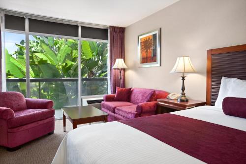 a hotel room with a bed and two chairs at Ramada by Wyndham Sunnyvale/Silicon Valley in Sunnyvale