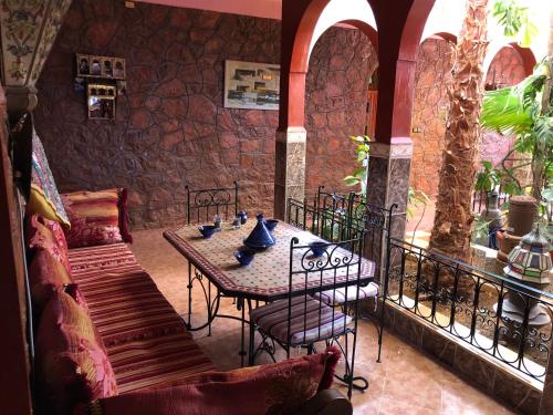 een tafel en stoelen in een kamer met een stenen muur bij Villa Siliya maga Cœur vallée amlen tafraout in Tafraoute