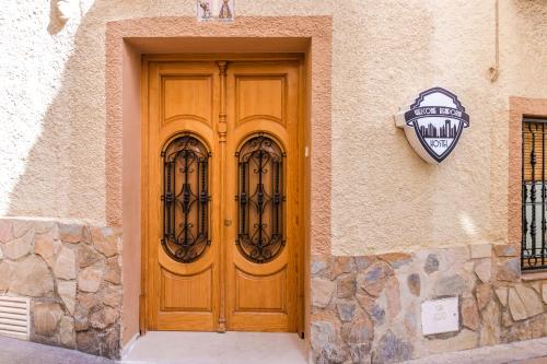 drewniane drzwi na boku budynku z zegarem w obiekcie Hostel Welcome Benidorm w mieście Benidorm