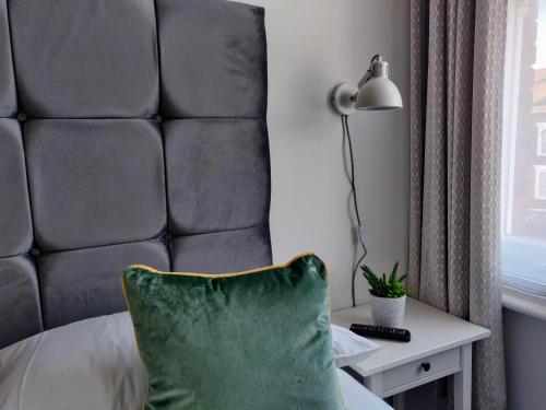 a bed with a green pillow and a lamp on a table at The Wincheap B&B in Canterbury