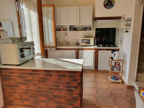 a kitchen with white cabinets and a brick counter top at Maison dans un village calme in Carla-de-Roquefort