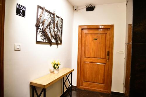 a room with a wooden door and a table with flowers at Xcel Luxury Hotel Apartments-Home Living Redefined in Mysore