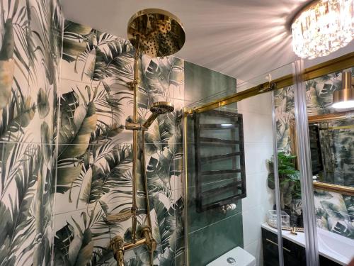 a bathroom with a shower with a plant wallpaper at Comfort Zone Ostróda Villa Apartment B in Ostróda