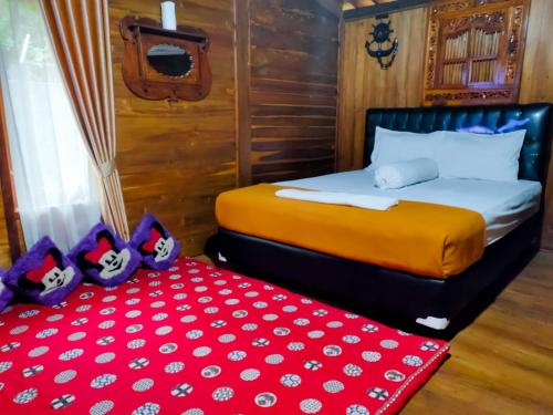 a bedroom with a bed and a red pillow at joglo house karinduaji madasari in Bulakbenda
