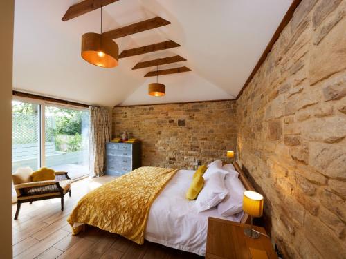 - une chambre avec un mur en pierre et un grand lit dans l'établissement Forest Farm Cottage, à Haywards Heath