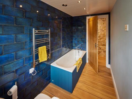 La salle de bains est pourvue d'une baignoire et de carrelage bleu. dans l'établissement Forest Farm Cottage, à Haywards Heath