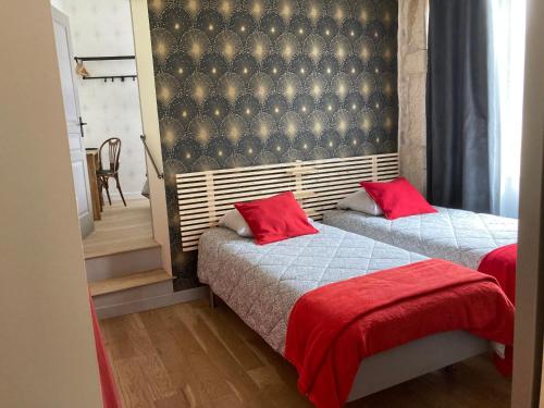 a bedroom with two beds with red pillows at L'Atelier 1 in Corcelles-les-Arts