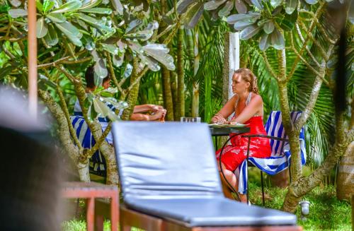 a woman sitting on a bench in front of some palm trees at Palm Paradise Cabanas & Villas Beach Resort in Tangalle