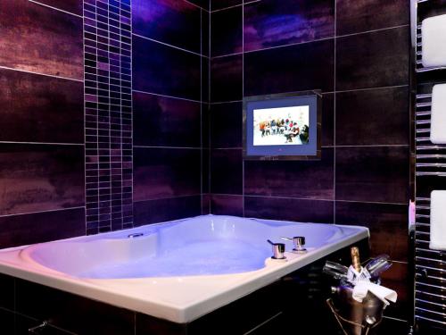 a bathroom with a tub with a tv on the wall at The Howbeck & The Retreat 5min to Lake, Restaurants & to the free SPA in Windermere