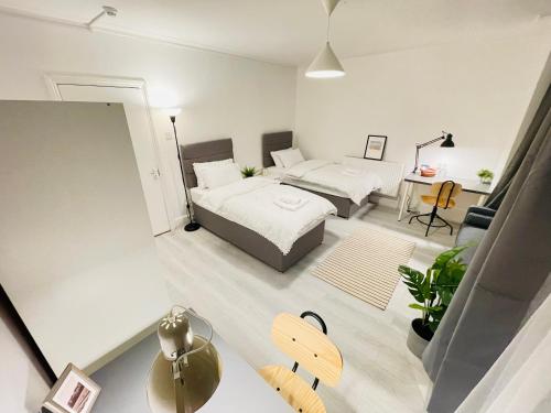 a bedroom with two beds and a table in a room at Leytonstone House - SleepyLodge in London