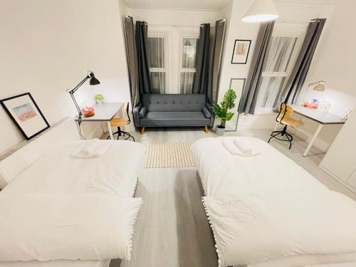 a living room with two white beds and a desk at Leytonstone House - SleepyLodge in London