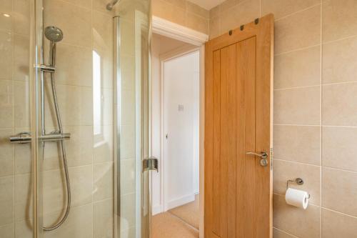 a bathroom with a shower and a wooden door at Shrimper's Cottage in Wadebridge