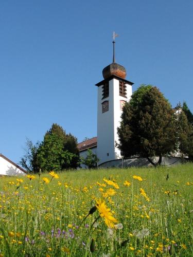 a church with a clock tower in a field of flowers at Gästehaus Johanna in Bad Wiessee
