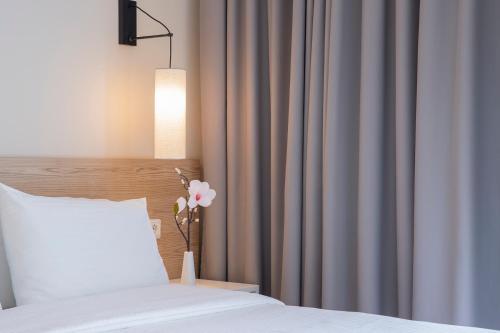 a bedroom with a bed and a curtain and a vase with a flower at Zefyros Sea View Hotel in Platamonas