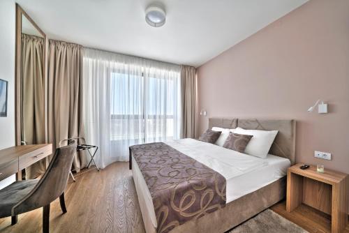 a hotel room with a large bed and a desk at Beograd na vodi - Belgrade Waterfront Riverside in Belgrade