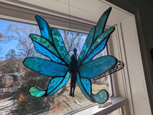 a blue glass butterfly hanging in a window at eKstasis Hostel & Urban Farm in Atlanta