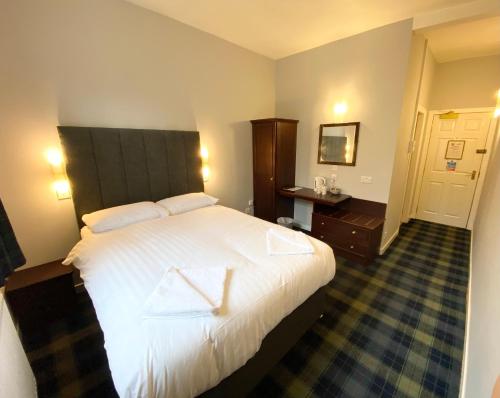a hotel room with a bed, chair, and nightstand at Lost Guest House Stirling in Stirling