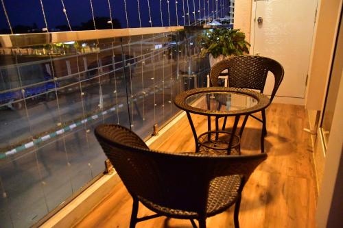 two chairs and a table on a balcony with a window at Xcel Luxury Hotel Apartments-Home Living Redefined in Mysore