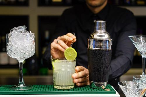 a bartender is making two cocktails on a table at Hotel Patria in Pistoia