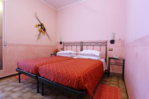 a bedroom with a bed with red sheets and white pillows at Hotel Astoria in Tabiano