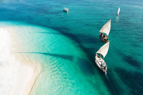 two boats in the water next to a beach at Gold Zanzibar Beach House & Spa in Kendwa