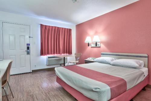a hotel room with a bed with a red wall at Motel 6-Flagstaff, AZ - West - Woodland Village in Flagstaff