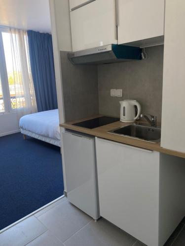 a kitchen with a sink and a bed in a room at Appart' hôtel 7 sensation in Bougival