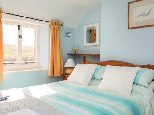 een slaapkamer met een bed en een raam bij Honeysuckle Cottage in Kingsbridge