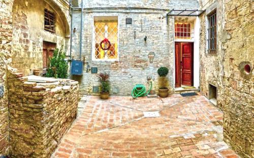 a stone building with a red door and some plants at Le Loggine del Pignattello in Siena