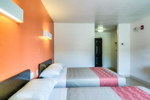 two beds in a room with an orange wall at Motel 6-Arlington Heights, IL - Chicago North Central in Arlington Heights