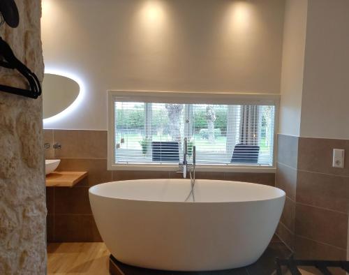 Pura Vida del Rio في Oud-Ade: حوض أبيض كبير في الحمام مع نافذة