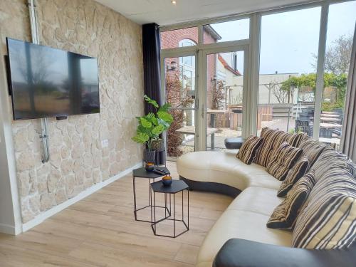 Pura Vida del Rio في Oud-Ade: غرفة معيشة مع أريكة وتلفزيون