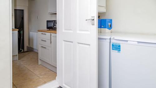 a kitchen with white cabinets and a white door at Hibbert Galore in Barrow in Furness
