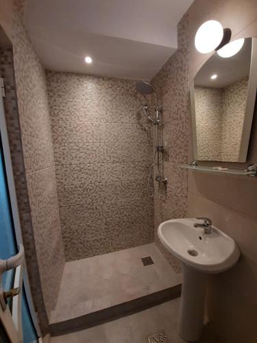 a bathroom with a shower and a sink and a mirror at Hotel Pescarus in Mamaia