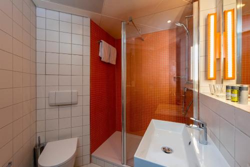 a bathroom with a shower and a toilet and a sink at ibis Styles Berlin Treptow in Berlin