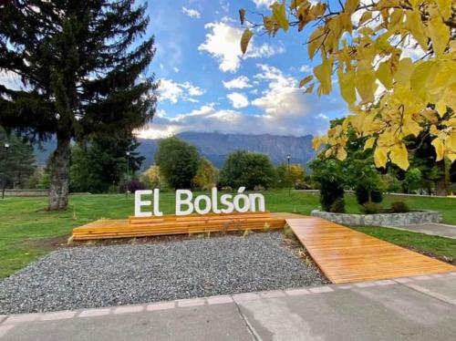 a bench with the el bolson sign in a park at Encanto Patagónico in El Bolsón
