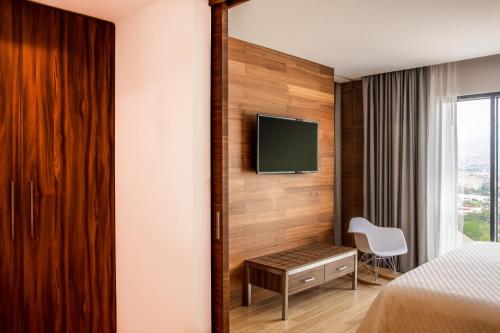 a hotel room with a desk and a tv on a wall at Fiesta Inn Tuxtla Fashion Mall in Tuxtla Gutiérrez