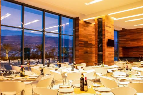 a restaurant with white tables and chairs and large windows at Fiesta Inn Tuxtla Fashion Mall in Tuxtla Gutiérrez