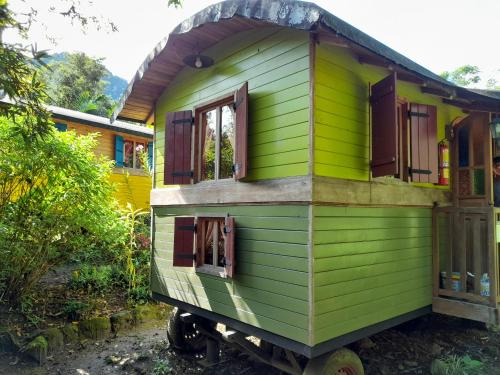 a green house with windows on a yard at Hosteria La Roulotte - Mindo in Mindo