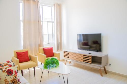 a living room with a tv and two chairs at Apartamento no Farol da Barra. Vista deslumbrante para o mar! No circuito do Carnaval. Ao lado do Porto da Barra ! in Salvador