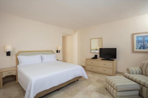 a bedroom with a white bed and a television at Fiesta Inn Veracruz Malecon in Veracruz