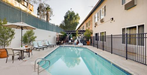 a swimming pool with tables and chairs next to a building at Ayres Hotel Corona East in Corona