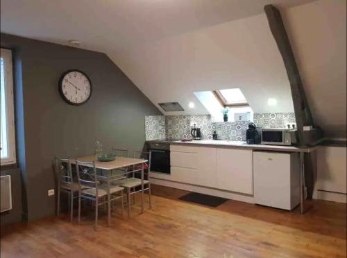 a kitchen with a table and a clock on the wall at Logement à Brive, proche centre-ville et gare, avec climatisation - internet fibre - Stationnements gratuit in Brive-la-Gaillarde