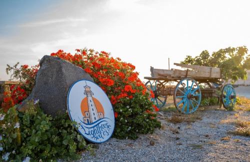 a sign for a lighthouse and a cart with flowers at The Lighthouse Sunset View Suites in Akrotiri