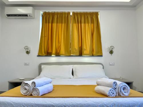 a bed with towels on it with a yellow window at Casa Aprea in Sorrento