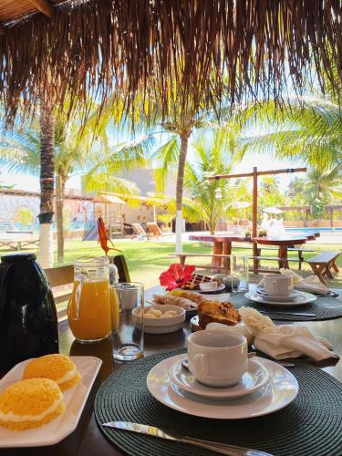 a table with a breakfast of orange juice and food at Pousada o Casarão in São Miguel dos Milagres