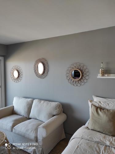 a living room with a couch and mirrors on the wall at appartement belle vue in Courseulles-sur-Mer