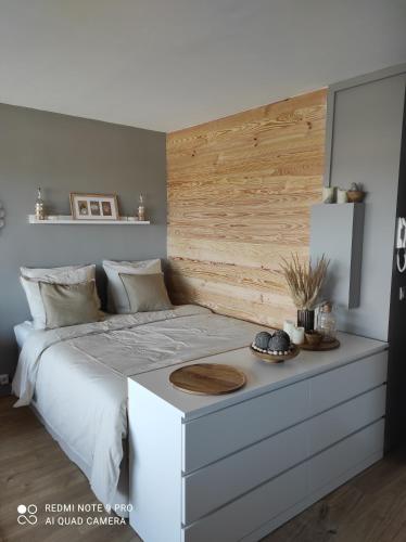 a bedroom with a white bed with a wooden headboard at appartement belle vue in Courseulles-sur-Mer